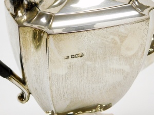 A George V silver three piece tea service, comprising teapot, two handled sugar bowl and milk jug, each with a shaped body and angular handles on a shaped pedestal base, the teapot with an ebonised knop and handle, makers marks for Stevenson and Law, Shef - 4