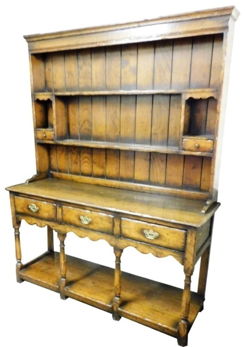 An oak dresser in 18thC style, the back with a moulded cornice above two shelves and two vacant recesses with lower drawer compartments, the base with a moulded edge above three frieze drawers on turned legs, with pot board, 176cm high, 137cm wide, 46cm d