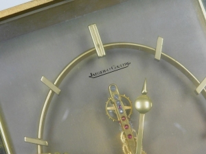 A Jaeger LeCoultre brass mantel clock in the Japanese style, the brass skeleton eight day movement inset with red/pink coloured stones, the dial flanked by two panels depicting birds, branches, leaves, etc., 15cm high, 20cm wide, 5cm deep. - 2
