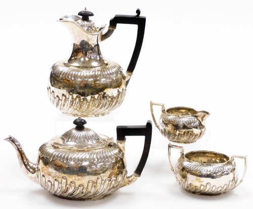 A Victorian Neoclassical design silver four piece service, with a part fluted design body and ebonised handles and knops, makers mark for RM and EH, London 1888, 33oz gross.