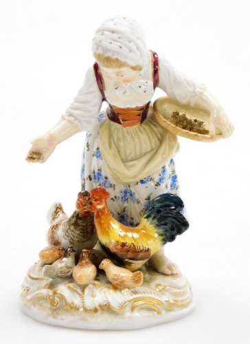 A Meissen porcelain figure group, of a young girl feeding cockerel, chicken and chicks, on a gilt highlighted circular base, blue cross swords mark to underside and impress number 115, 11cm high. (AF)