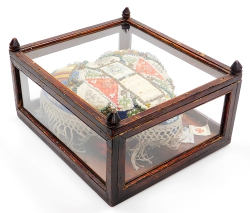 A Devonshire Regiment forget me not heart shaped sweetheart pin cushion, with various beaded detailing and Devonshire Regiment central shield, in a stained oak case, 19cm high, 30cm wide, 34cm deep.