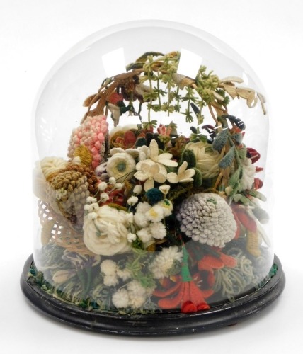An early 20thC woolwork knitted floral basket, with various pom pom flowers and vines, in a wicker basket on an ebonised base with glass dome, 35cm high.