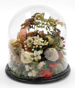An early 20thC woolwork knitted floral basket, with various pom pom flowers and vines, in a wicker basket on an ebonised base with glass dome, 35cm high.
