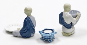 Three Lladro porcelain ornaments, comprising a Lladro figure of a seated monk with bowl, 14cm high, a figure of a kneeling monk carrying bowl, 15cm high, and a candle stand, 4cm high. (3) - 2