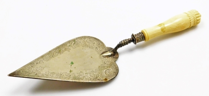 A late 19th/ early 20thC presentation trowel, the plated blade decorated with flowers, scrolls etc., with an ivory handle, 36cm long.