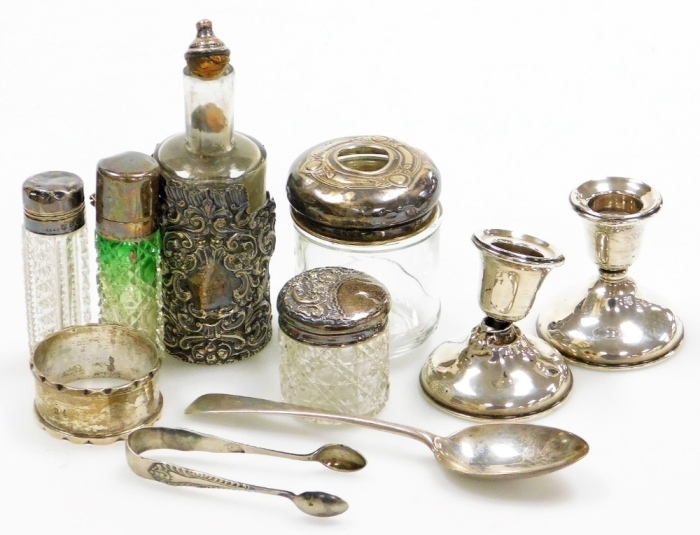 A collection of small silver, to include various glass and silver topped dressing table and scent bottles, a silver napkin ring, a pair of silver dwarf candlesticks, of plain form, Birmingham 1916, etc. (many pieces AF)