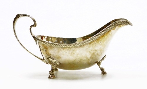 An Elizabeth II silver sauce boat, with a gadrooned border, shaped handle and three shell cast supports terminating in hoof shaped feet, makers marks for Coopers Brothers and Sons, Sheffield 1966, 9oz, 20cm wide.