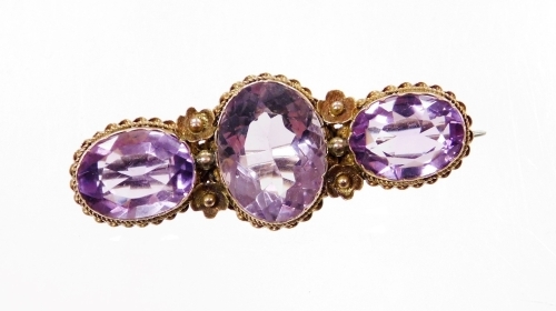 A Victorian 9ct gold amethyst bar brooch, set with three oval amethysts, each in a woven floral setting, 4cm wide, 5.2g all in, boxed.