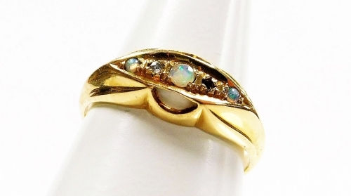 An 18ct gold opal and diamond gypsy ring, the central panel set with three opals and two tiny diamonds, on a flared design outer border, ring size L, 2.7g all in.