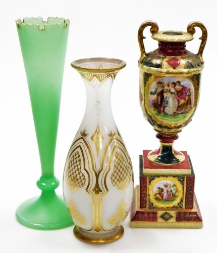 A continental two handled vase on stand, the body depicting various classical figures, signed Haufmann, with gilt highlights, 38cm high, a milk glass baluster shaped vase, with a flared rim with gilt highlights, 33cm high, and a green frosted glass long s