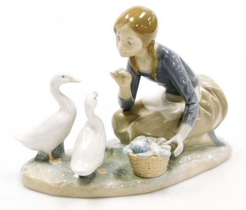A Lladro porcelain figure group, of a girl with basket feeding geese, 22cm wide.