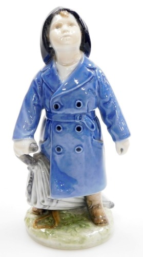 A Royal Copenhagen porcelain figure of young boy in raincoat with umbrella, on a circular base, stamped in green to underside with blue wave mark, 17cm high.