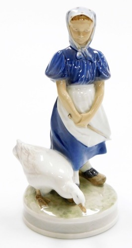 A Royal Copenhagen porcelain figure of a young girl with goose, on a circular base, green printed mark and blue wave mark to underside, 23.5cm high.