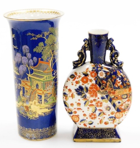 A Carlton ware cylindrical vase, on a blue ground decorated with Oriental house, trees, etc., 26cm high, and a late 19thC Imari pattern moon flask vase, with gilt highlights, 22.5cm high. (2)