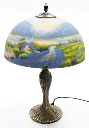 A Thomas Kinkade table lamp, the reverse decorated shade decorated with a field and cottage scene, on a cast metal base, 57cm high.