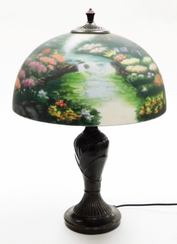 A Thomas Kinkade table lamp, the reverse decorated shade decorated with a meadow scene, on a cast metal base, 57cm high.