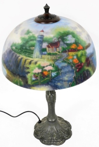 A Thomas Kinkade table lamp, the reverse decorated shade decorated with a cottage, lighthouse and sea scape, on a cast metal base, 66cm high.