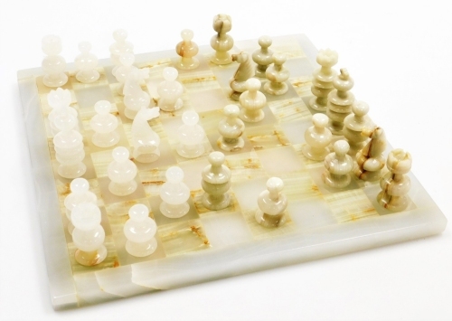 A pale green and white onyx chess board, with various chess pieces.