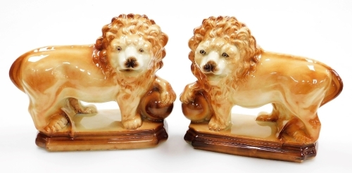 A pair of 19thC Staffordshire pottery lions, each in standing pose, with orb under front paw, each on a moulded stepped base, circa 1850, 30cm high. (2)