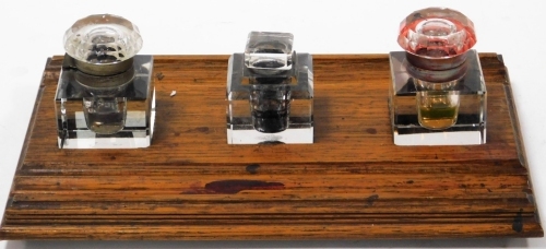An early 20thC oak inkstand, with three cut glass ink wells, 35cm x 22cm.