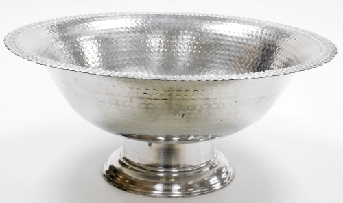 A large base metal centrepiece bowl, of circular form, on compressed stem and circular foot, partially hammered overall, with shaped rim, unmarked, 63cm wide.