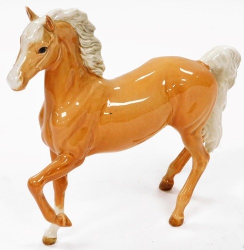 A 20thC Beswick Palomino horse, front leg raised, printed marks beneath, 18cm high.