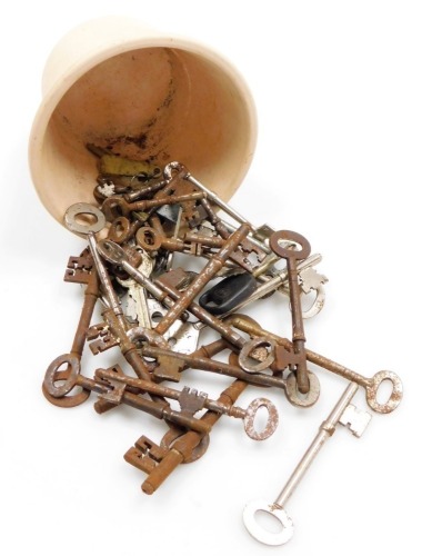 Various vintage keys, an iron example with oval top, 10cm wide, various others, etc., contained in a pottery planter of small proportion.