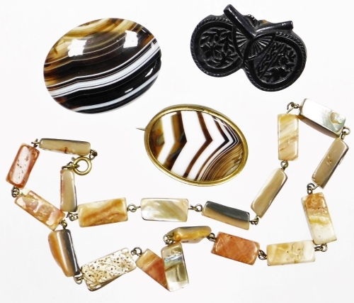 A group of stone set jewellery, to include a Victorian jet two fan brooch, 4cm wide, a brown agate single pin back brooch, 4cm wide, and a brown agate and gilt metal brooch, 3.5cm wide, together with a natural stone necklace. (4)
