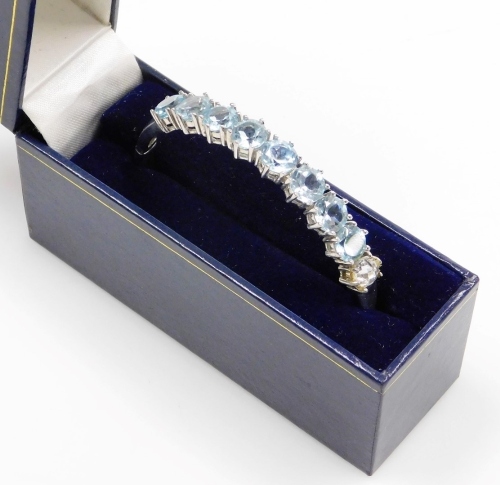 A silver aquamarine cuff bracelet, set with eight aquamarines, and one later replacement clear glass stone, white metal marked 925, 6cm diameter, boxed.