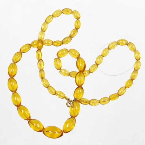 A set of imitation amber beads, each of graduated design, on string, with yellow metal clasps, unmarked, 54cm long.
