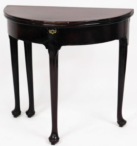 An 18thC mahogany demi lune tea table, with fold over top on pad feet with brass escutcheon, 75cm high, 81cm wide, 40cm deep.