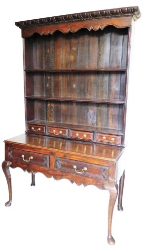 An 18thC style oak dresser of small proportion, a carved fixed cornice raised above three Delft racks and four spice drawers, the subsection set with two further drawers on cabriole legs terminating in pad feet, 168cm high, 115cm wide, 52cm deep.