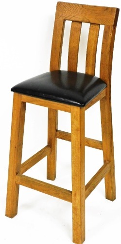 A light oak childs highchair, with overstuffed leatherette seat, on square block legs, joined by plain stretchers, 105cm high.