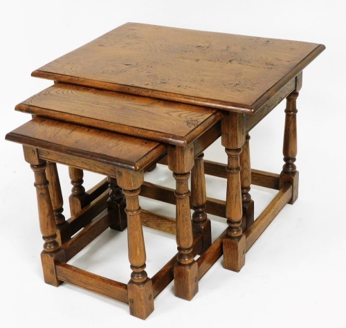 A Titchmarsh Goodwin style oak nest of three tables, each of rectangular form, on turned legs, terminating in block feet, the largest 47cm high, 61cm wide, 47cm deep.