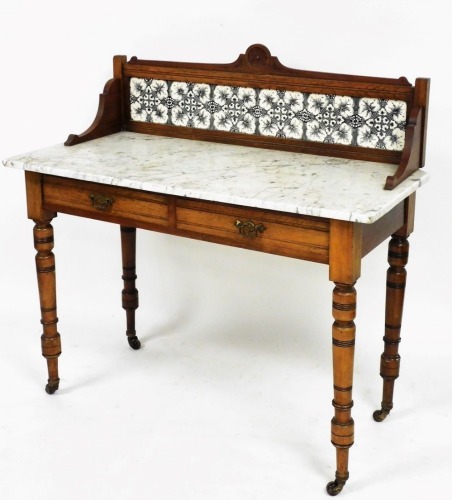 An Edwardian tiled and marble topped wash stand, of rectangular form, with three part back, with two frieze drawers on turner legs, terminating in castors, 100cm high, 107cm wide, 52cm deep.