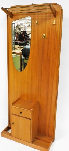 A retro teak hall stand, circa 1970s, with metal rails, shaped mirror and fixed pegs, above cupboard and drawer on plain base, 184cm high, 82cm wide, 26cm deep.