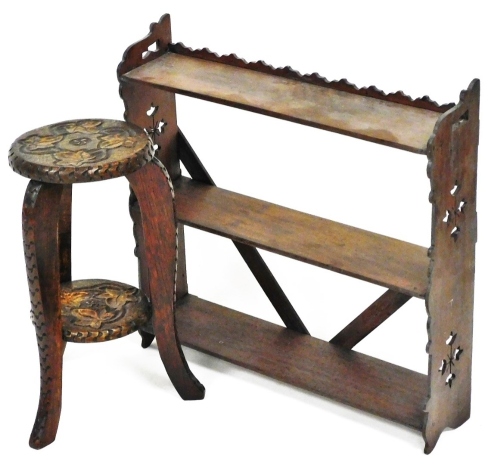 A heavily carved and pokerwork stand, of small proportion, the circular top set with leaves, raised on triple sabre legs joined by a circular under tier, 42cm high, the top 20cm diameter, and a mahogany three part hanging shelf. (2)