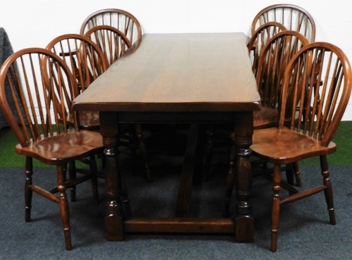 A 19thC style oak refectory table and eight (6+2) hoop back chairs, each chair with stick backs, turned single orb front legs and H stretchers, the refectory table on heavy baluster legs terminating in block feet, 79cm high, 220cm wide, 85cm deep.