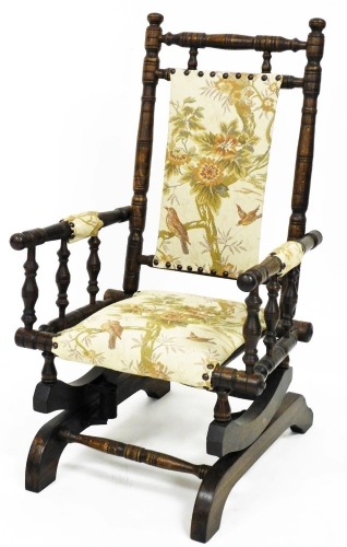 A miniature child's American style rocking chair, with turned frame and overstuffed back, arms and seat, on a rocker base, 74cm high.