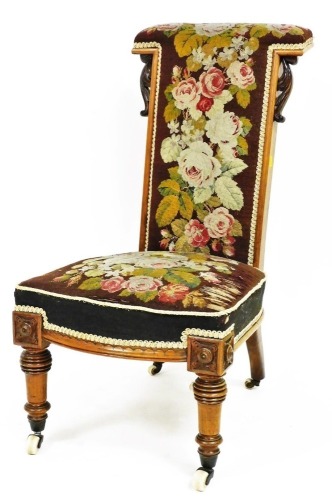 A Victorian walnut framed prie dieu chair, with petit point floral overstuffed back and seat, on turned front legs terminating in pot castors, 90cm high.