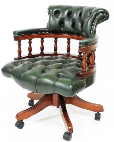 A mahogany office chair, in green leatherette, on shaped legs terminating in castors, 83cm high.