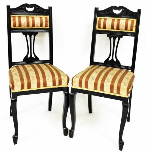 A pair of Edwardian walnut salon chairs, each with padded backs and seats, in Regency style striped floral material, on shaped front legs, 101cm high. (2)