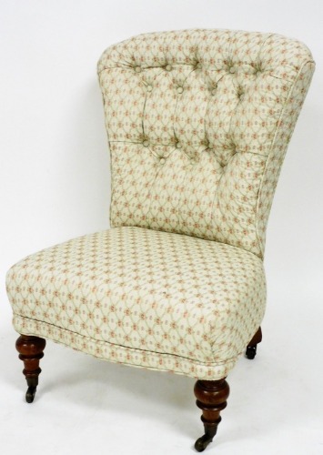 An Edwardian nursing chair, with overstuffed button back and seat in floral material, on turned front legs terminating in castors, 88cm high.
