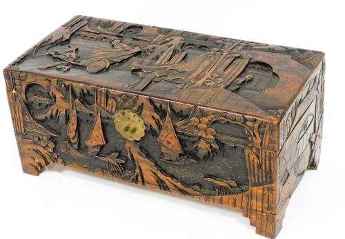 A 20thC camphor wood chest, of small proportion, heavily carved with Chinese figures, rickshaw, trees, buildings and water, with plain interior, on shaped stiles, 29cm high, 65cm wide, 30cm deep.