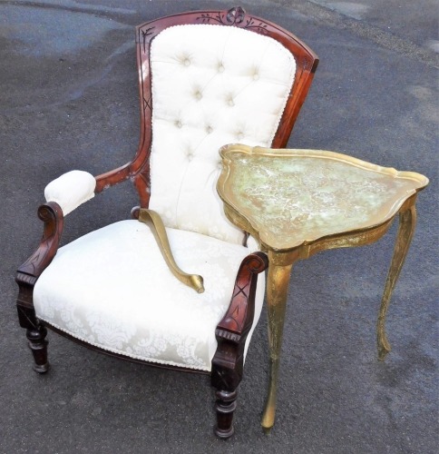 A late Victorian walnut armchair, with overstuffed back, arms and seat, on turned front legs, in later cream floral material, 98cm high, and a gilt shaped occasional table on three legs.