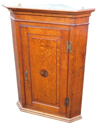 An 18thC oak hanging corner cabinet, the panelled door, centred by a sun motif on a plain moulded base with part fitted interior, 113cm high, 81cm wide, 48cm deep.