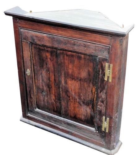 A 19thC oak hanging corner cupboard, the panel door revealing shelves, on a plain moulded base, 79cm high, 73cm wide, 37cm deep.