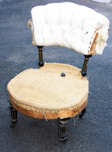A Victorian ebonised occasional chair, with overstuffed button back and circular seat, with turned front legs terminating in metal castors, 78cm high. (AF)