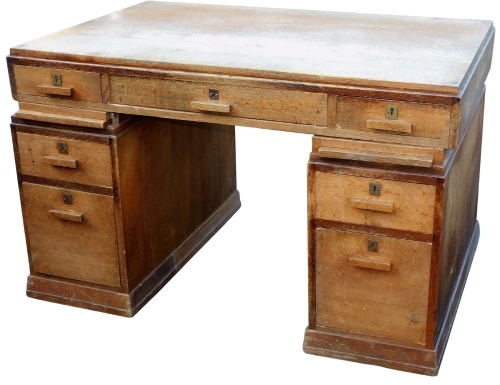 A 20thC oak twin pedestal desk, the rectangular top with three frieze drawers, with shaped handles, above six drawers, 78cm high, 124cm wide, 81cm deep.